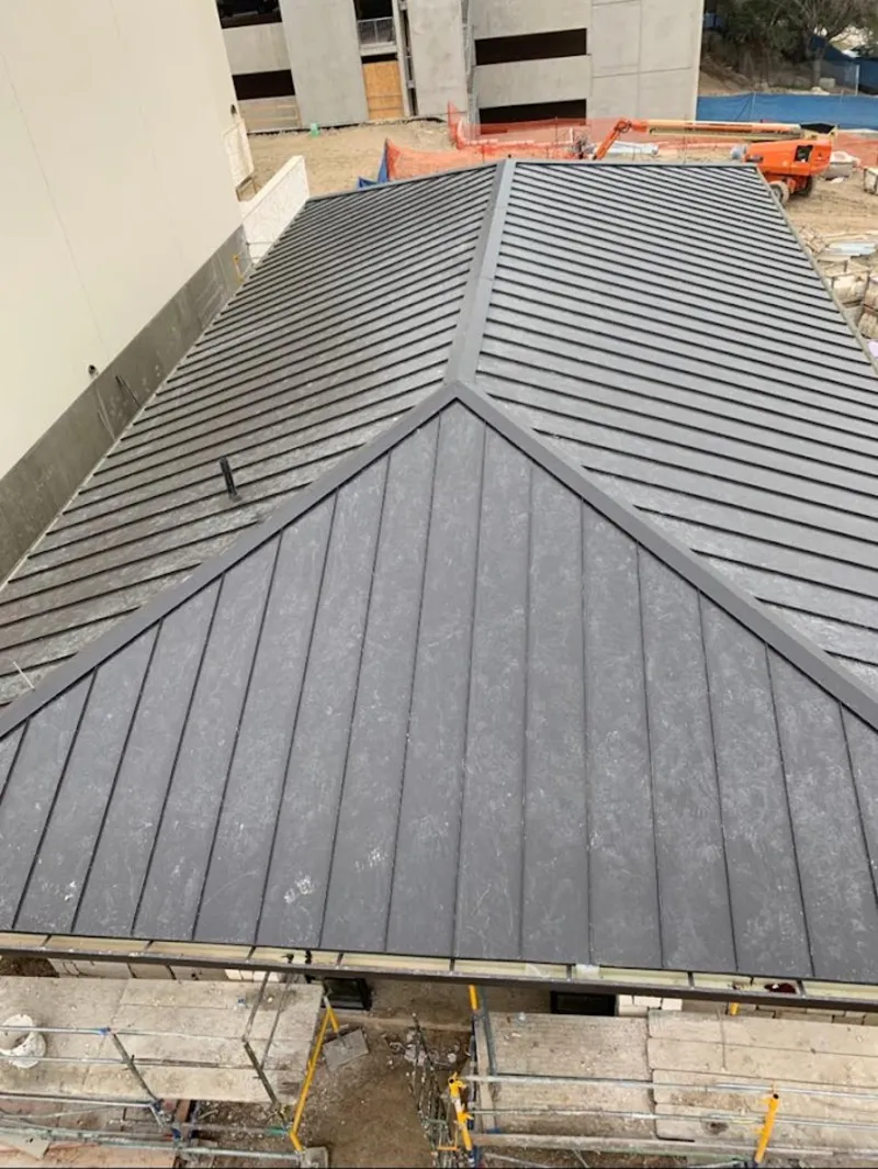 Commercial metal roof construction with crane equipment in Gray